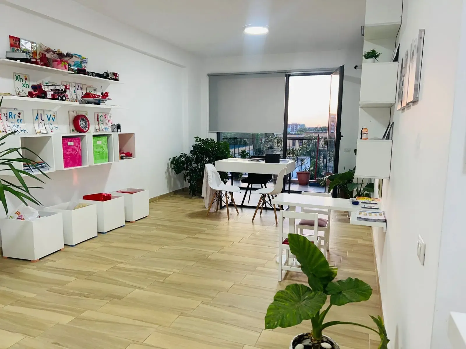 Dhoma e lojës e klinikës Speak Up, me dritare të madhe dhe lodra në rafte
